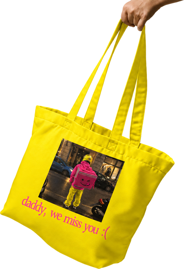 A hand holding a yellow tote bag with a photo of a courier with a pink FeedMe backpack and the text: daddy, we miss you :(